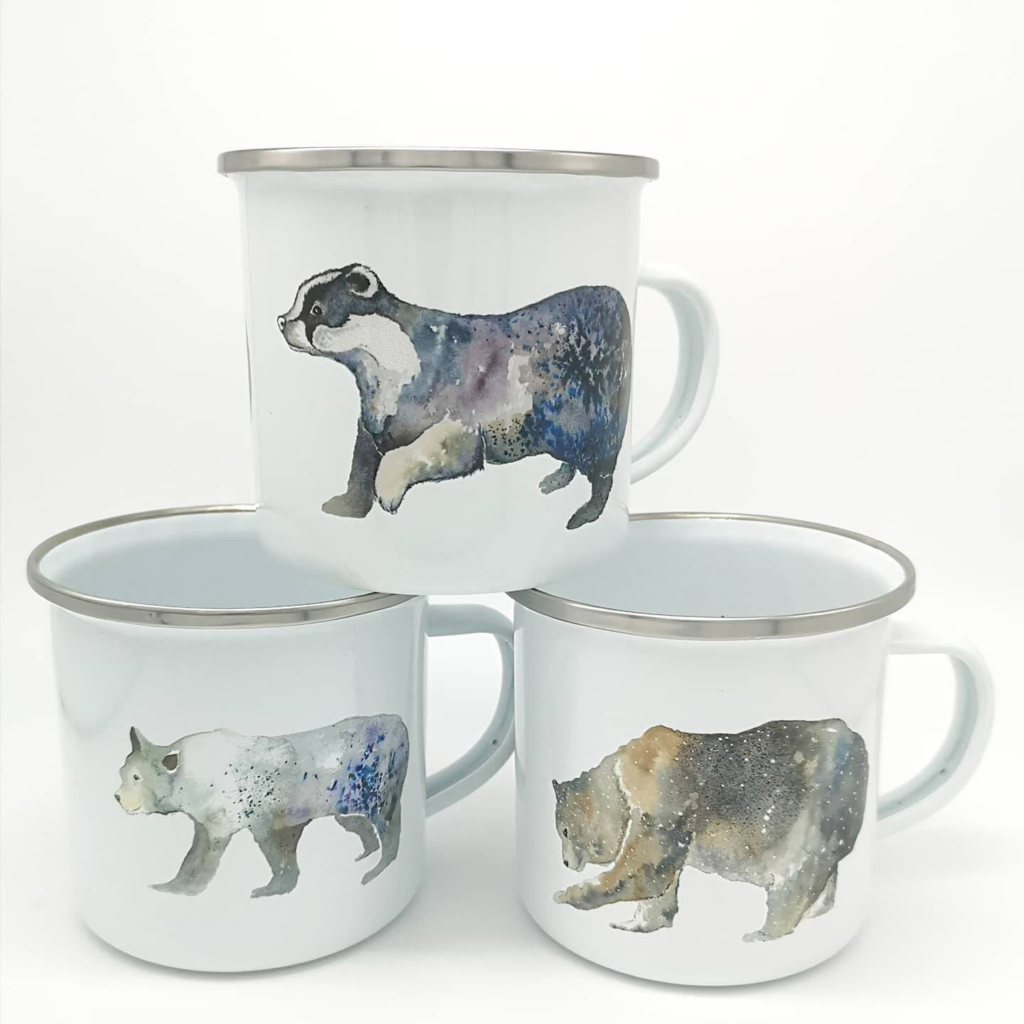 Enamel camping mugs on a white background. The mugs have illustrations of a badger, polar bear and grizzly bear on.