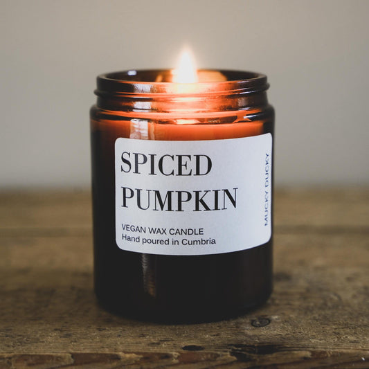 Mucky Ducky's Spiced Pumpkin candle burning on a rustic kitchen table